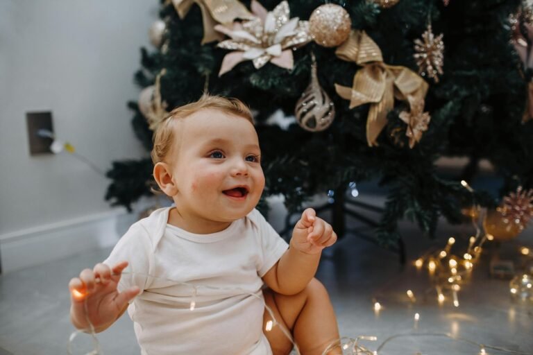 A baby sitting in front of a christmas tree