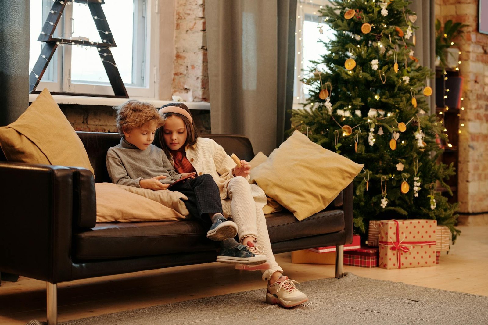 two kids sitting on a couch while looking at a digital tablet